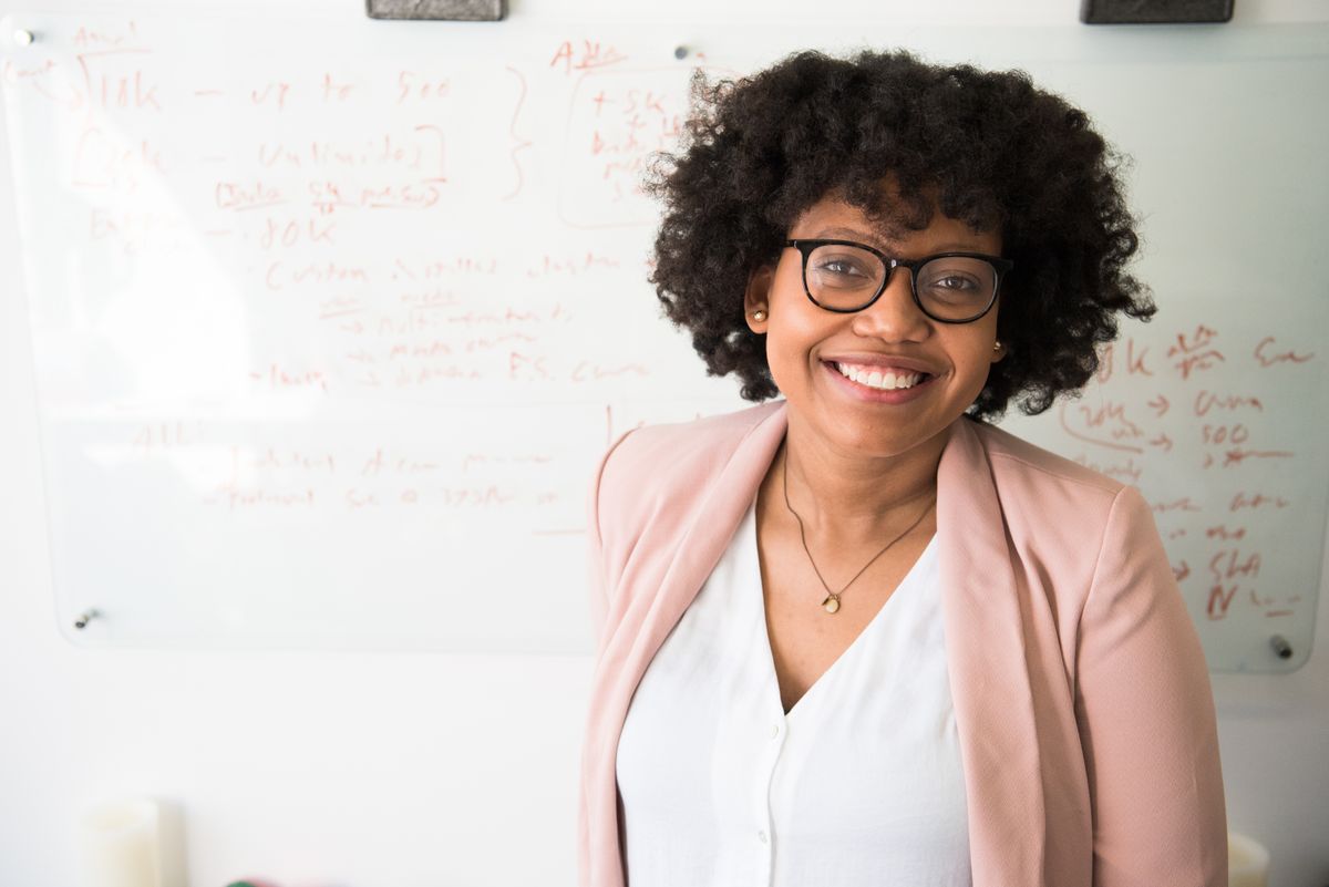 African businesswoman presenting custom software strategy on whiteboard with team in office